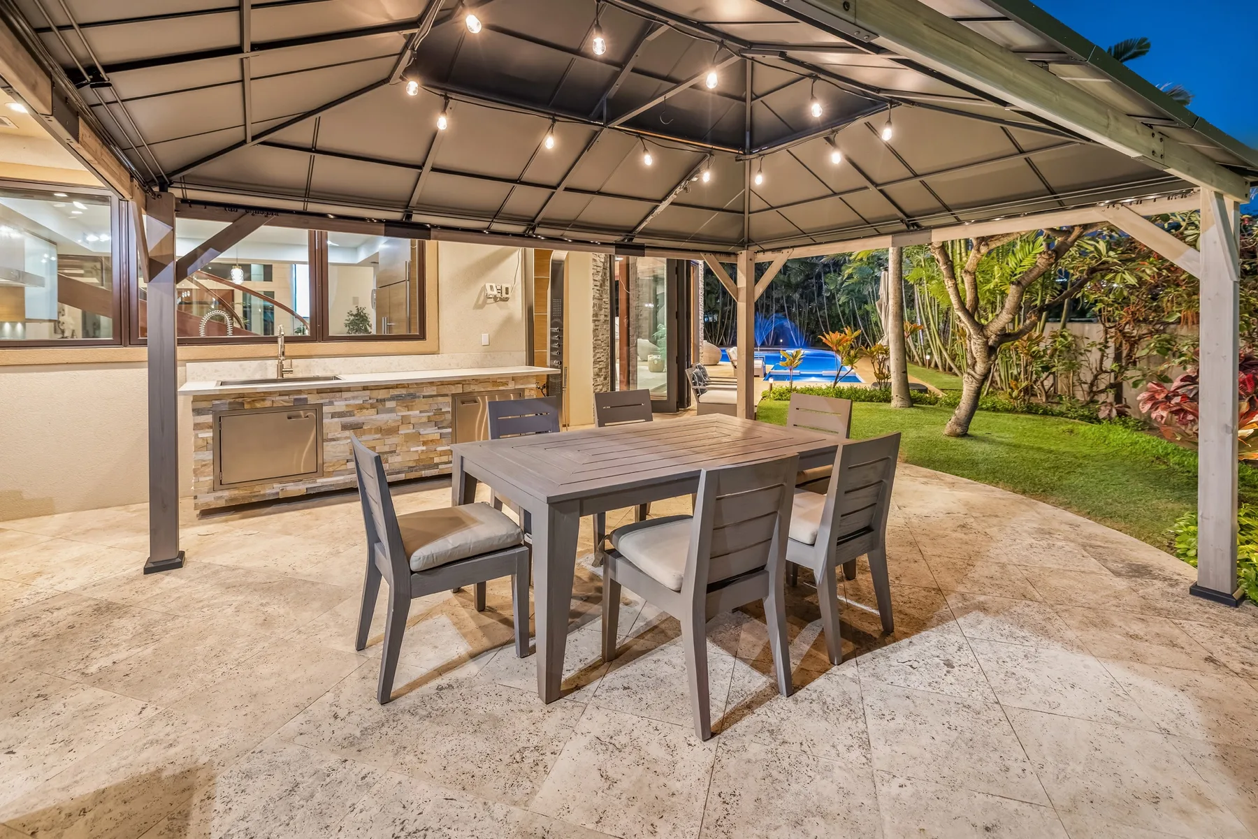 Una zona de comedor exterior cubierta con una mesa y sillas junto a un jardín.