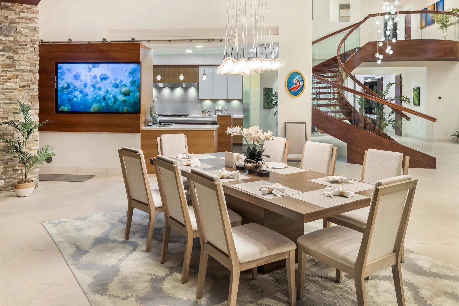 Un comedor con una mesa larga puesta bajo lámparas colgantes.