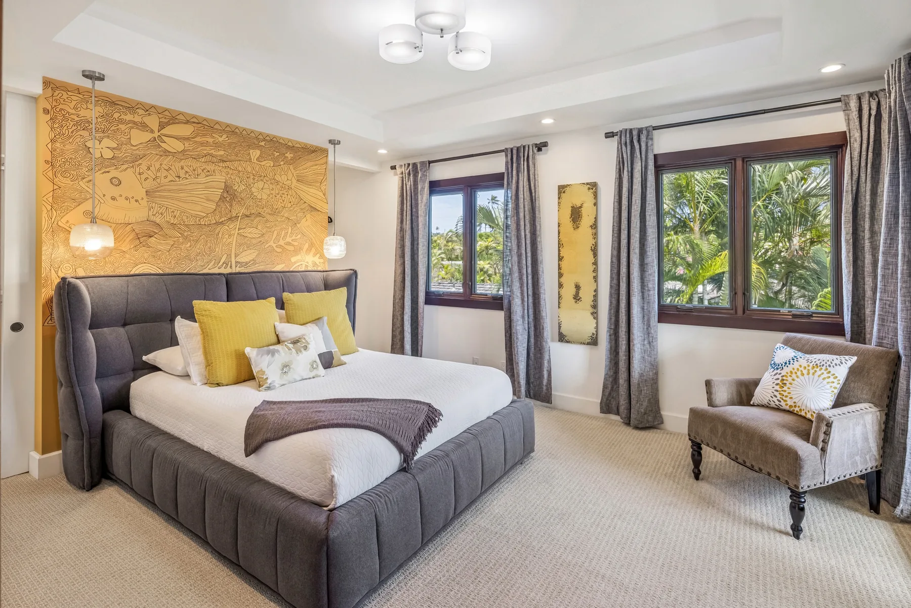 Un dormitorio con una cama grande, ventanas con cortinas y una zona de descanso acolchada.