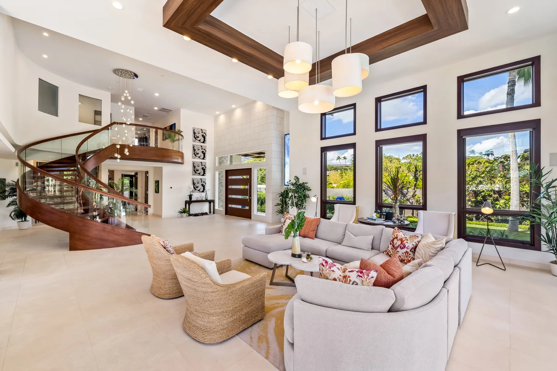 Una amplia sala de estar tiene una zona de asientos junto a ventanas altas y una escalera curva.