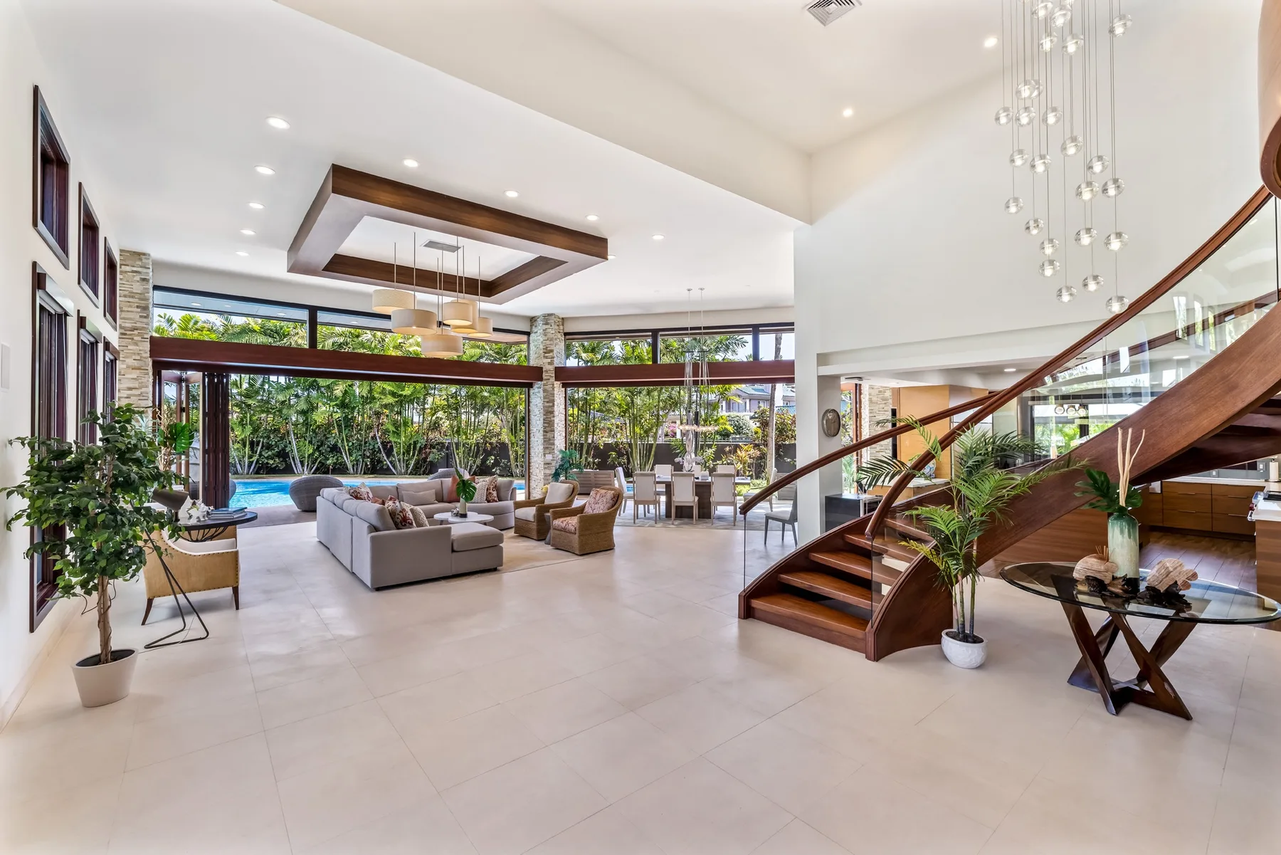 Una sala luminosa con asientos, grandes ventanales y una escalera curva.