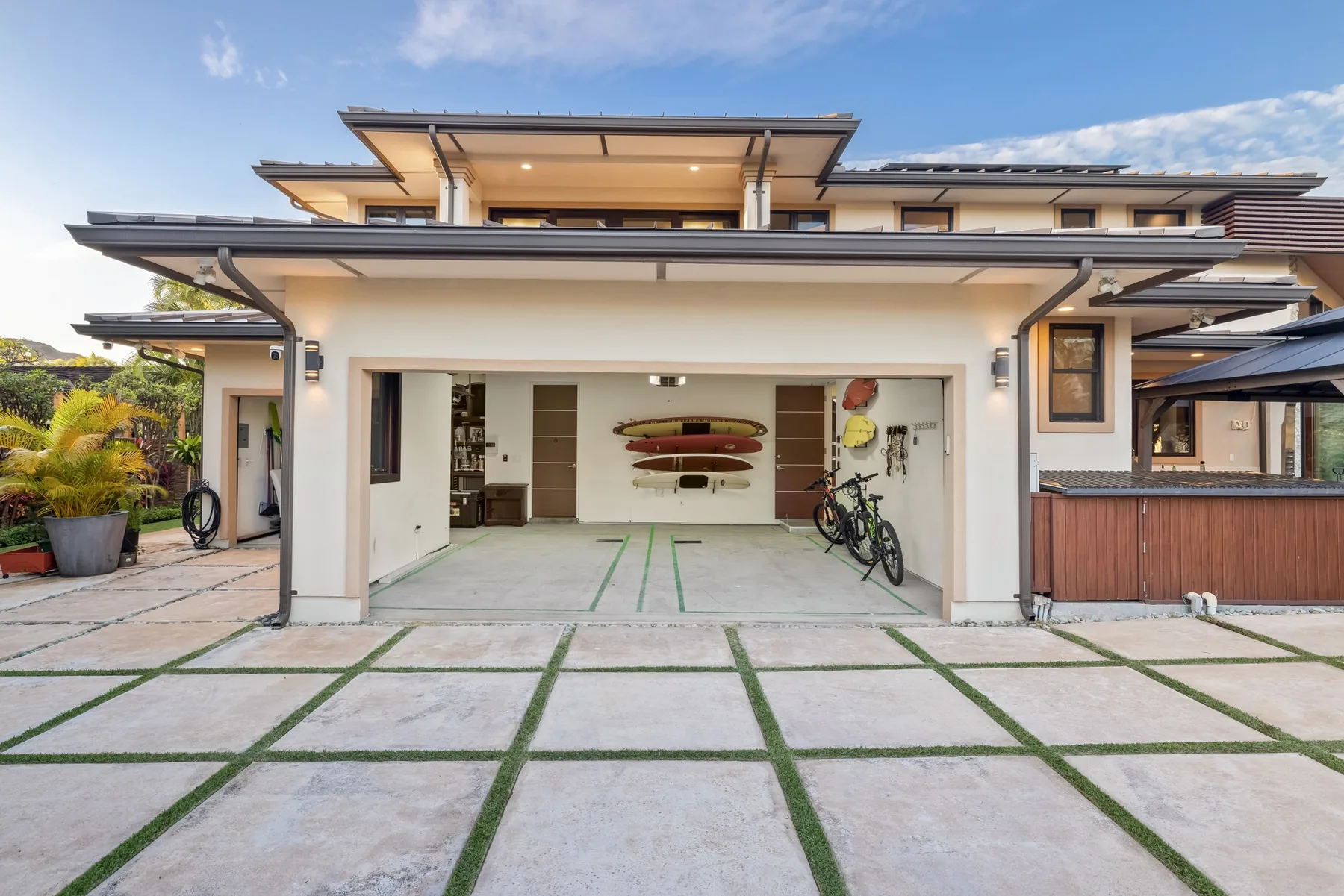 Una casa moderna con el garaje abierto y bicicletas junto a la entrada.