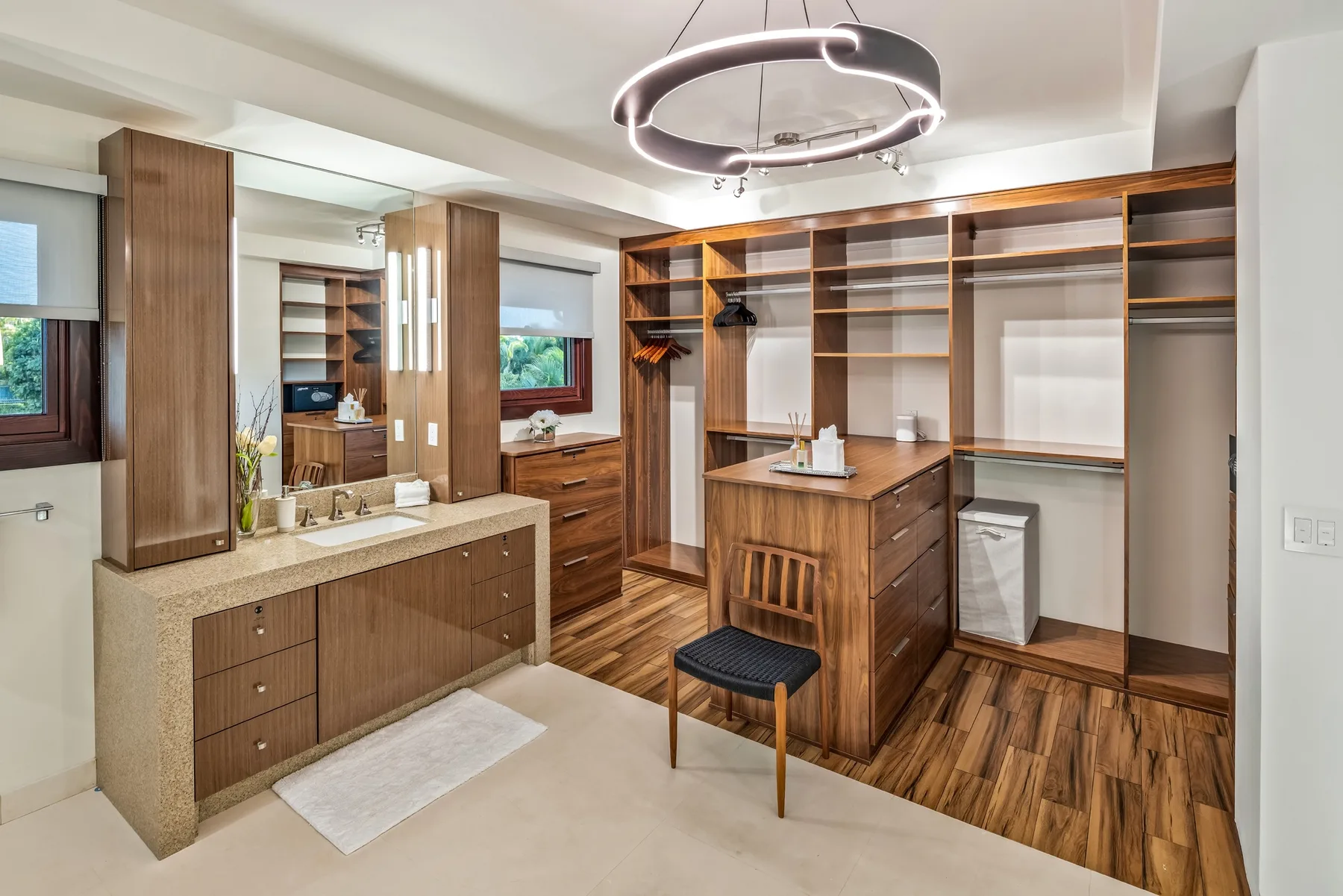 Un vestidor con armarios de madera, una encimera central y un taburete acolchado.