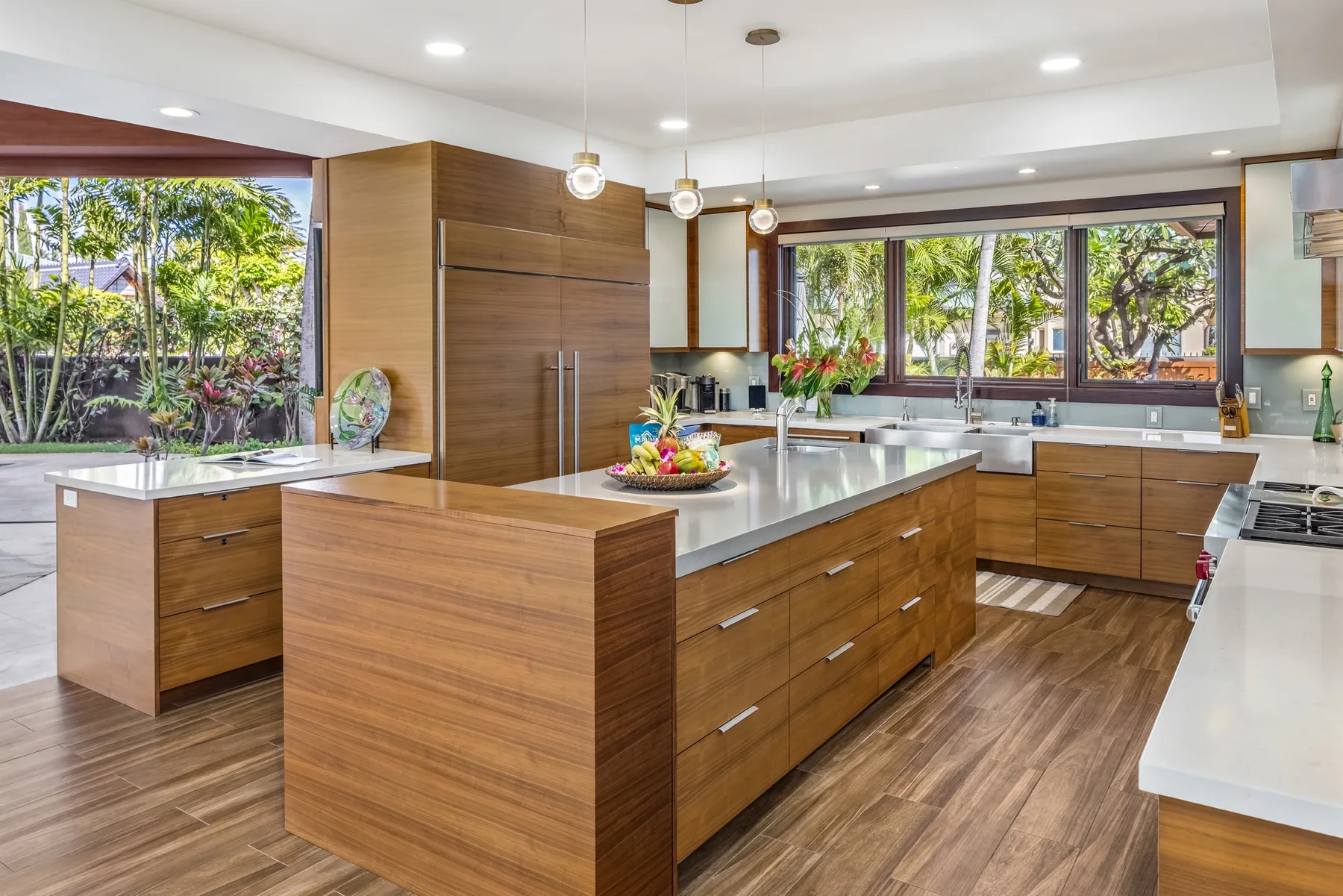 Una cocina amplia con gabinetes de madera, una isla central y grandes ventanas.