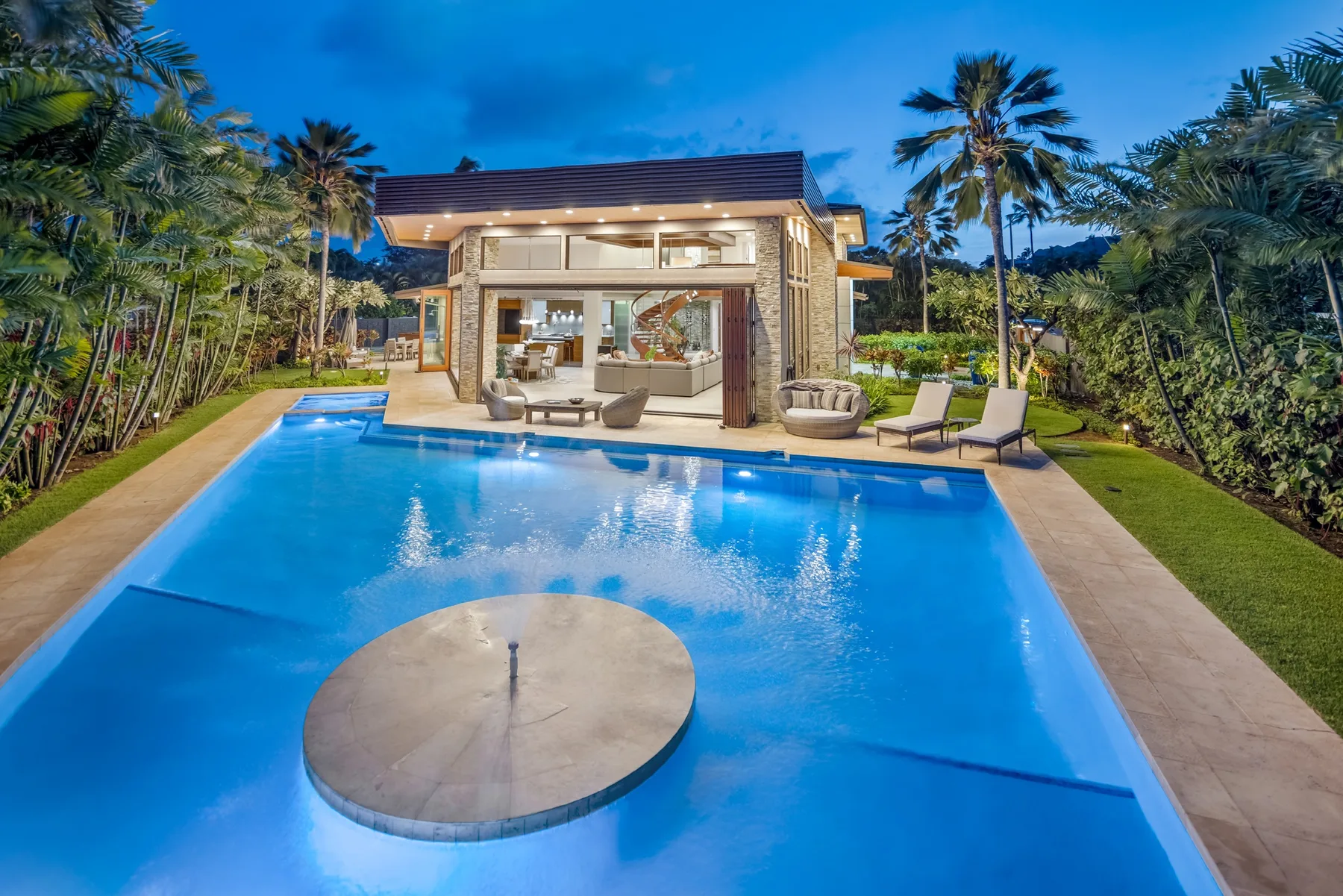 Una casa moderna da a una piscina rodeada de palmeras.