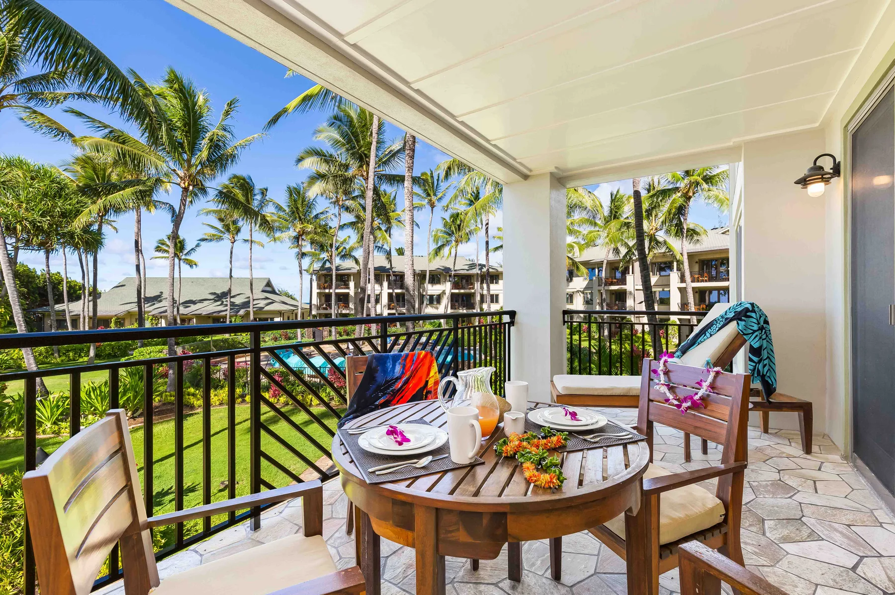 A covered outdoor dining area overlooks palm trees and landscaped grounds.