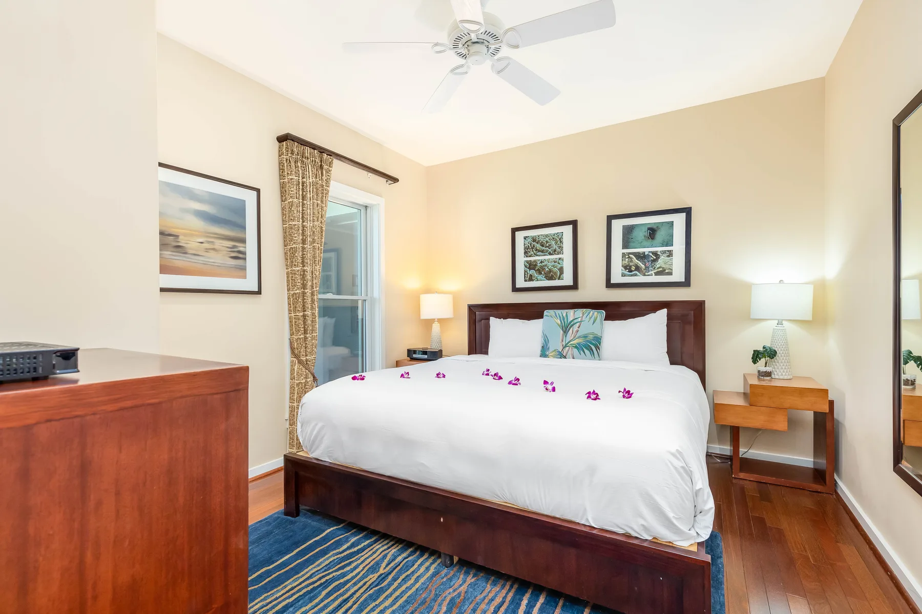 A bedroom with a neatly made bed, bedside tables, and a ceiling fan.