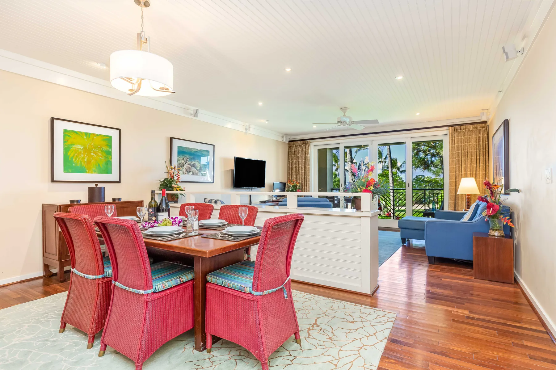 An open-plan dining and living area with red dining chairs and blue seating.