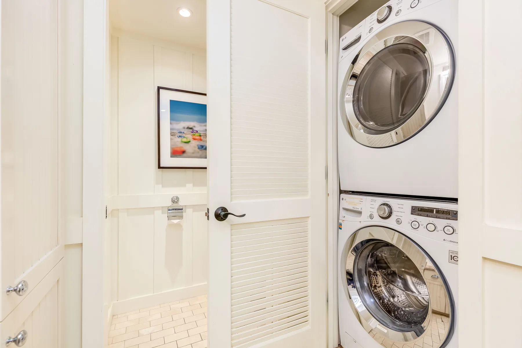 A laundry area with a stacked washer and dryer behind an open door.