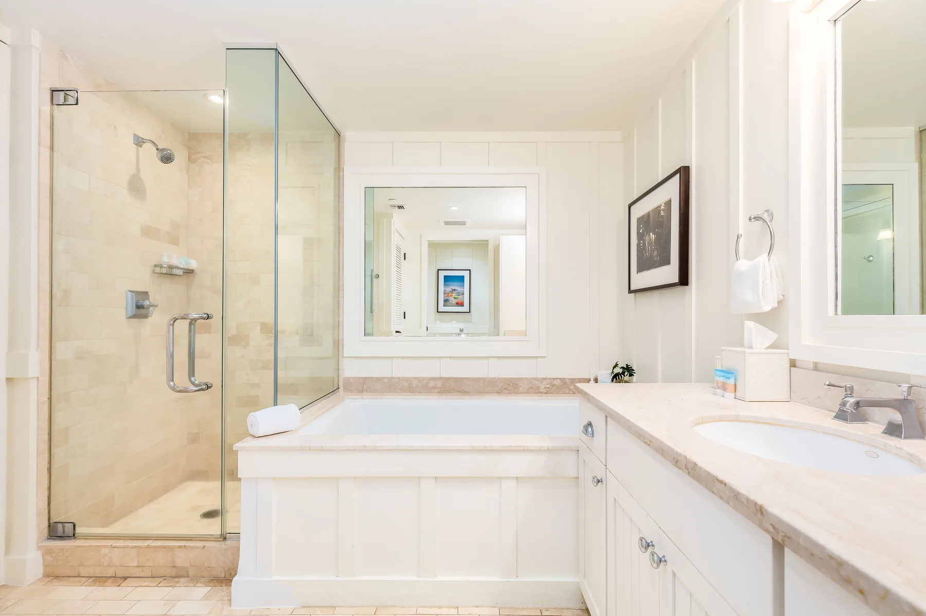 A bright bathroom with a glass shower and a long vanity.