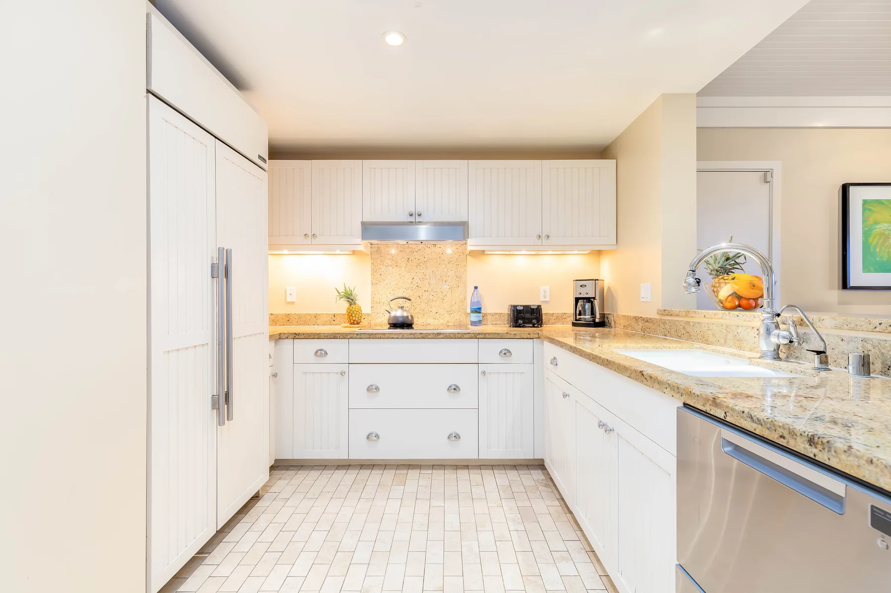 A bright kitchen with white cabinets and a stone countertop.