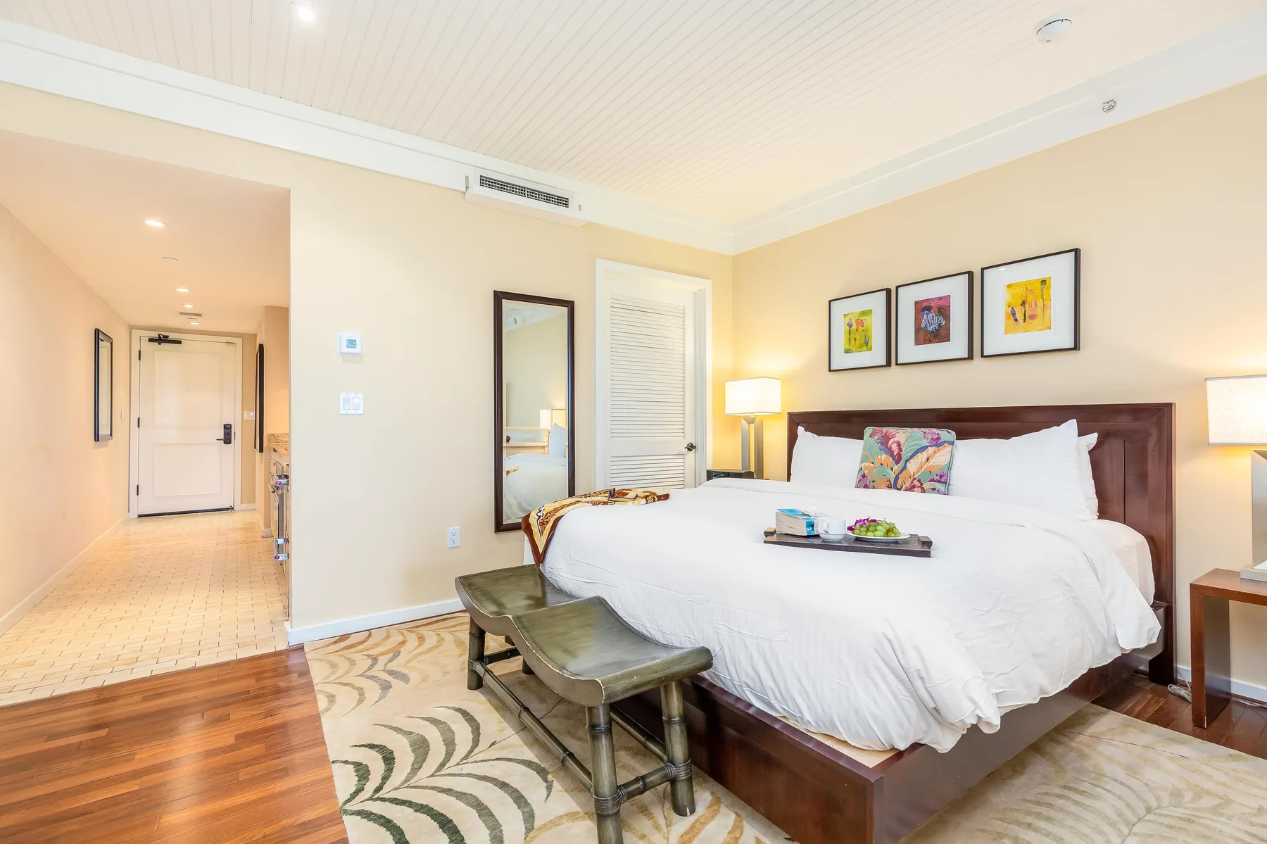 A bedroom with a large bed, bedside lamps, and framed artwork above it.