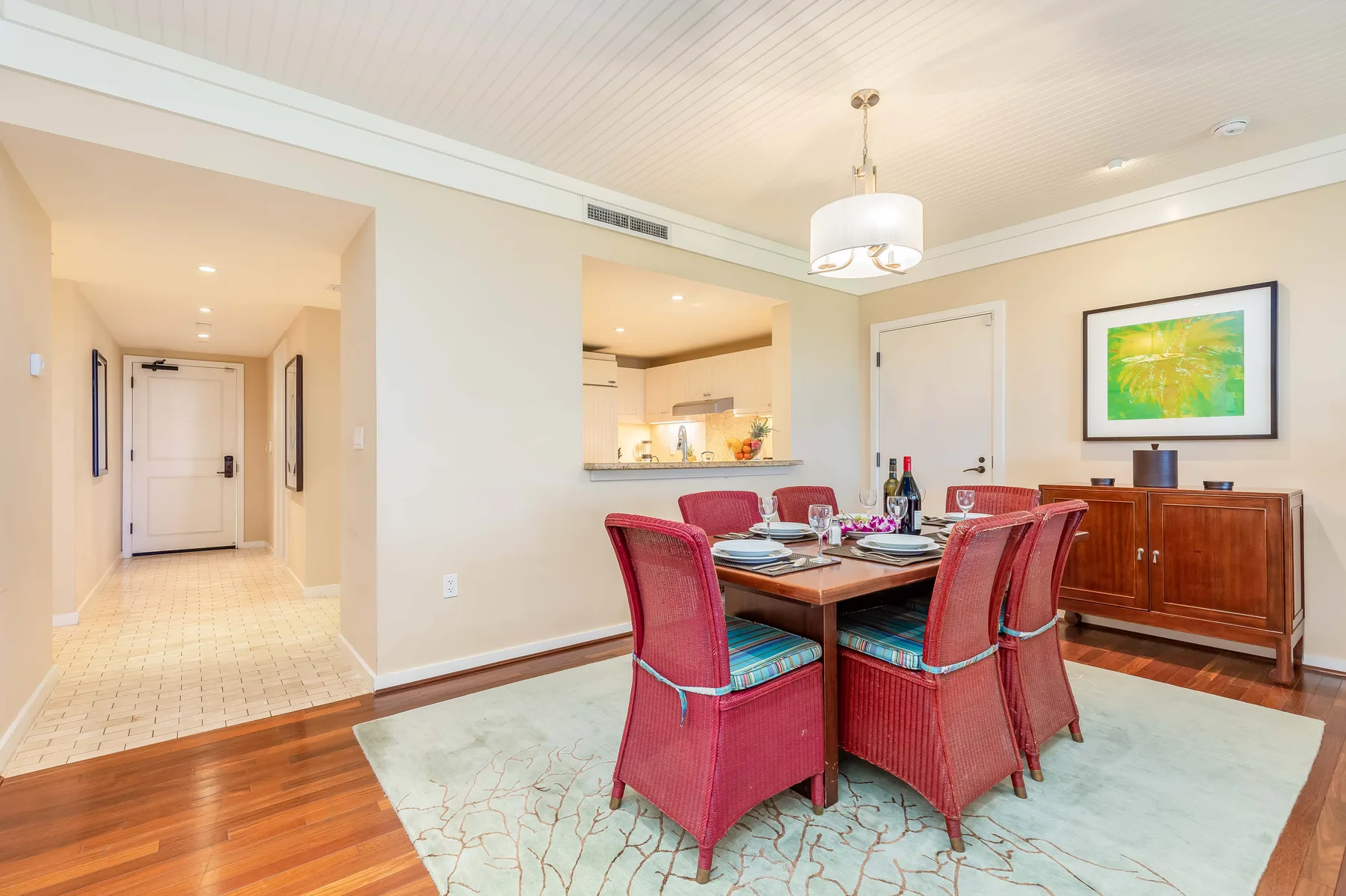 A dining room with a table, red seating, and a wooden sideboard.