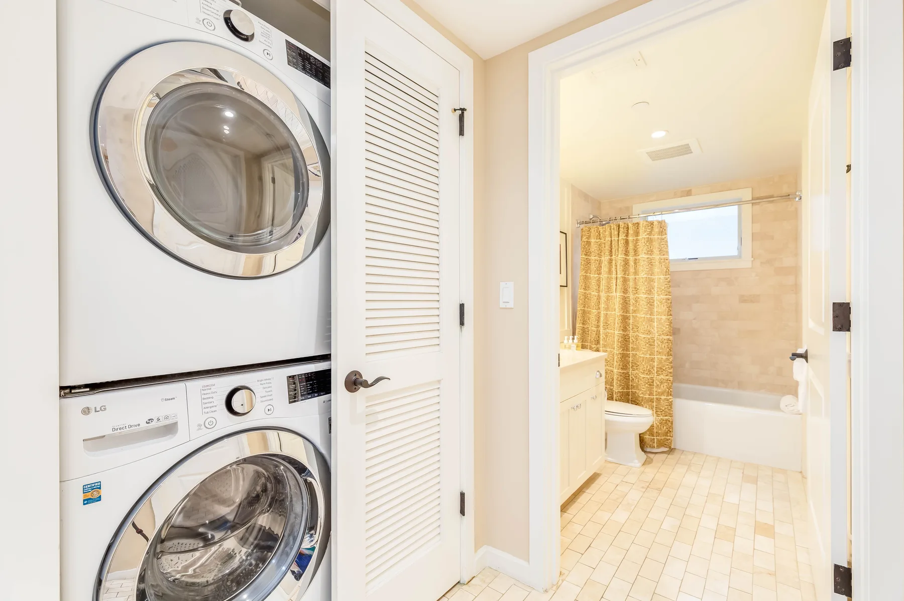 A bathroom with a bathtub and shower curtain, viewed through an open doorway.