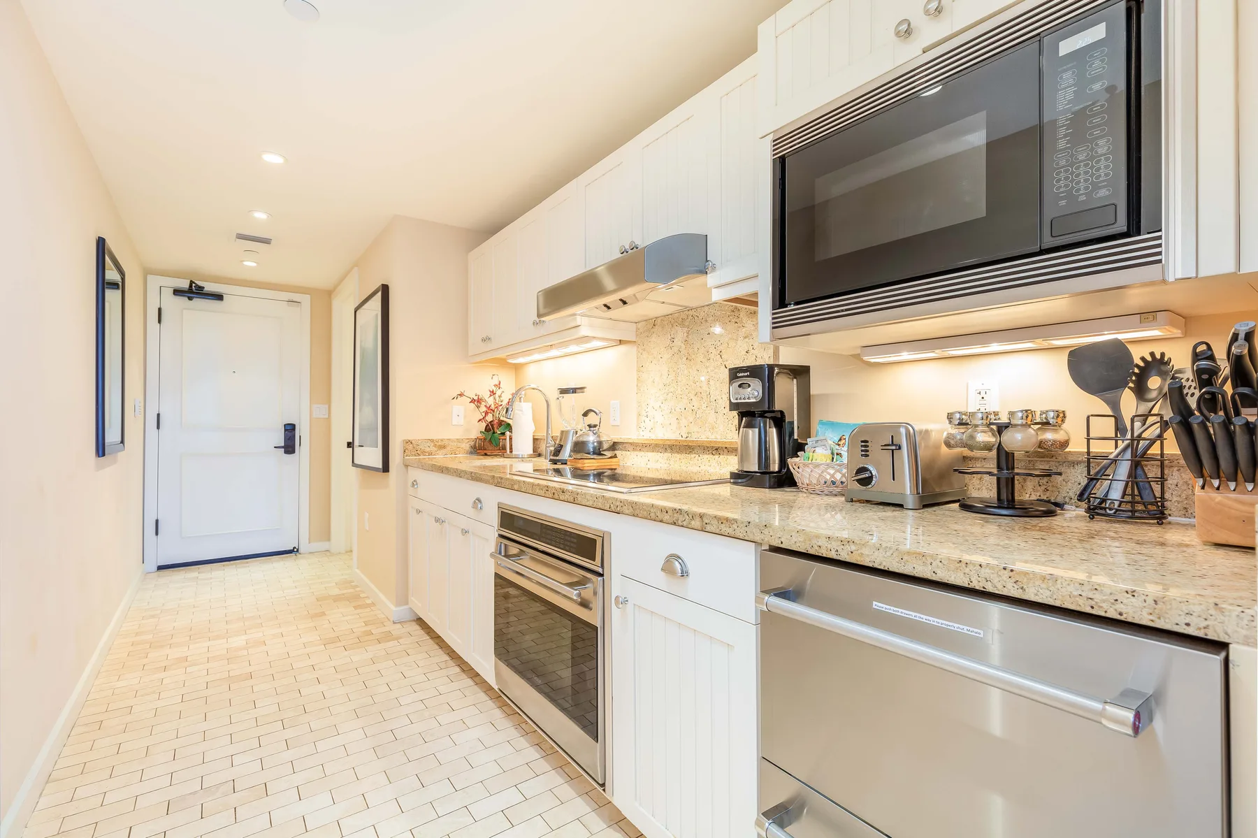 A bright kitchen with white cabinets, a countertop, and built-in appliances.
