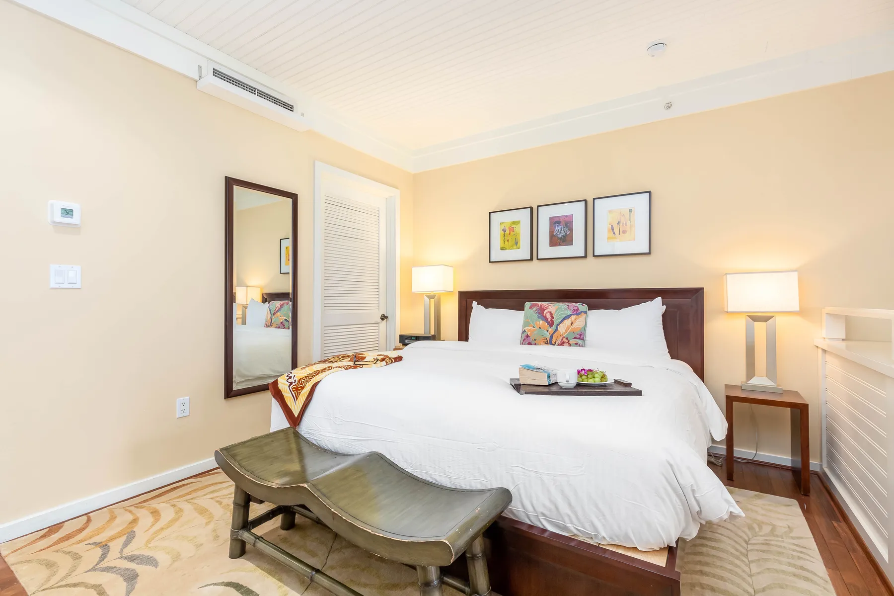 A bedroom with a large bed, bedside lamps, and a bench at the foot.