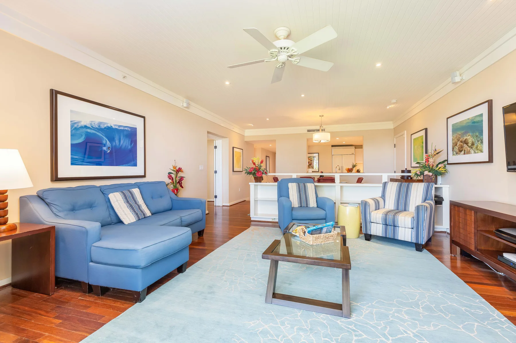 A living room with blue seating, a coffee table, and an open kitchen beyond.