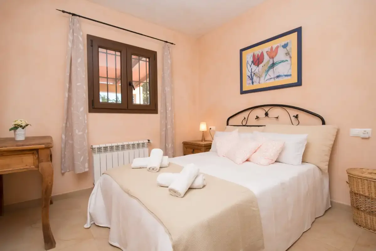 A bedroom with a neatly made bed and a window.