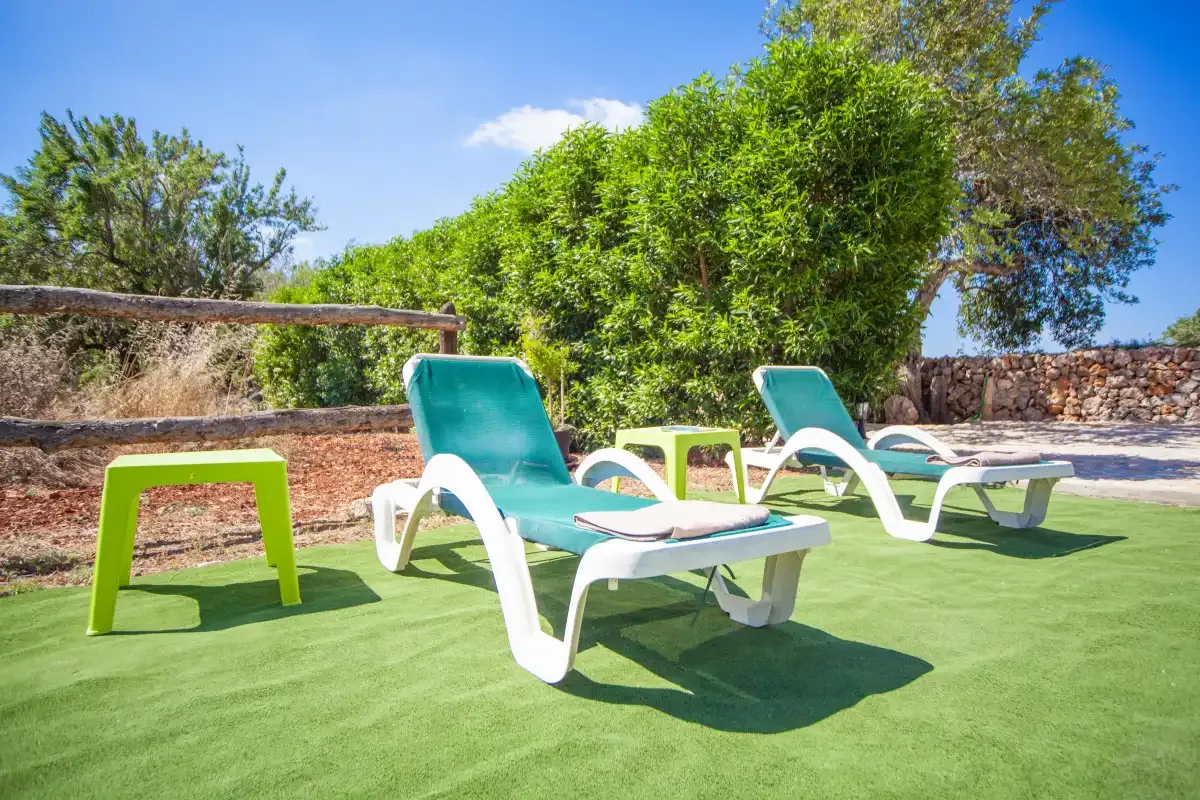 Outdoor seating area with turquoise loungers and green turf.