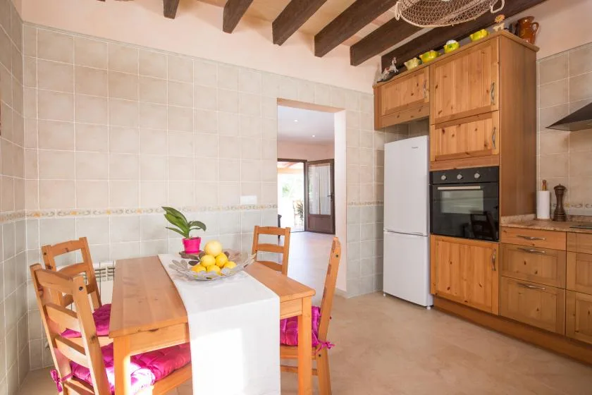 A dining area with a wooden table and built-in kitchen cabinetry.