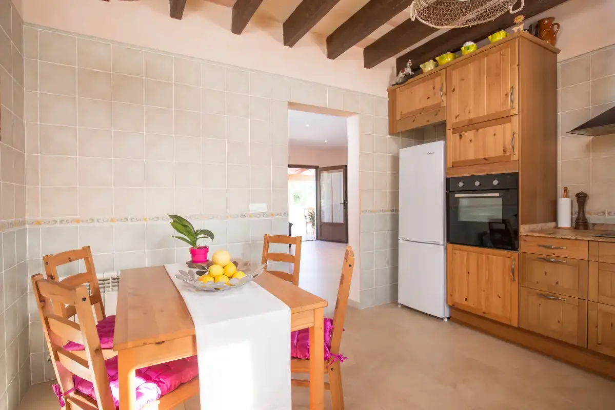 A dining area with a wooden table beside built-in kitchen cabinets.
