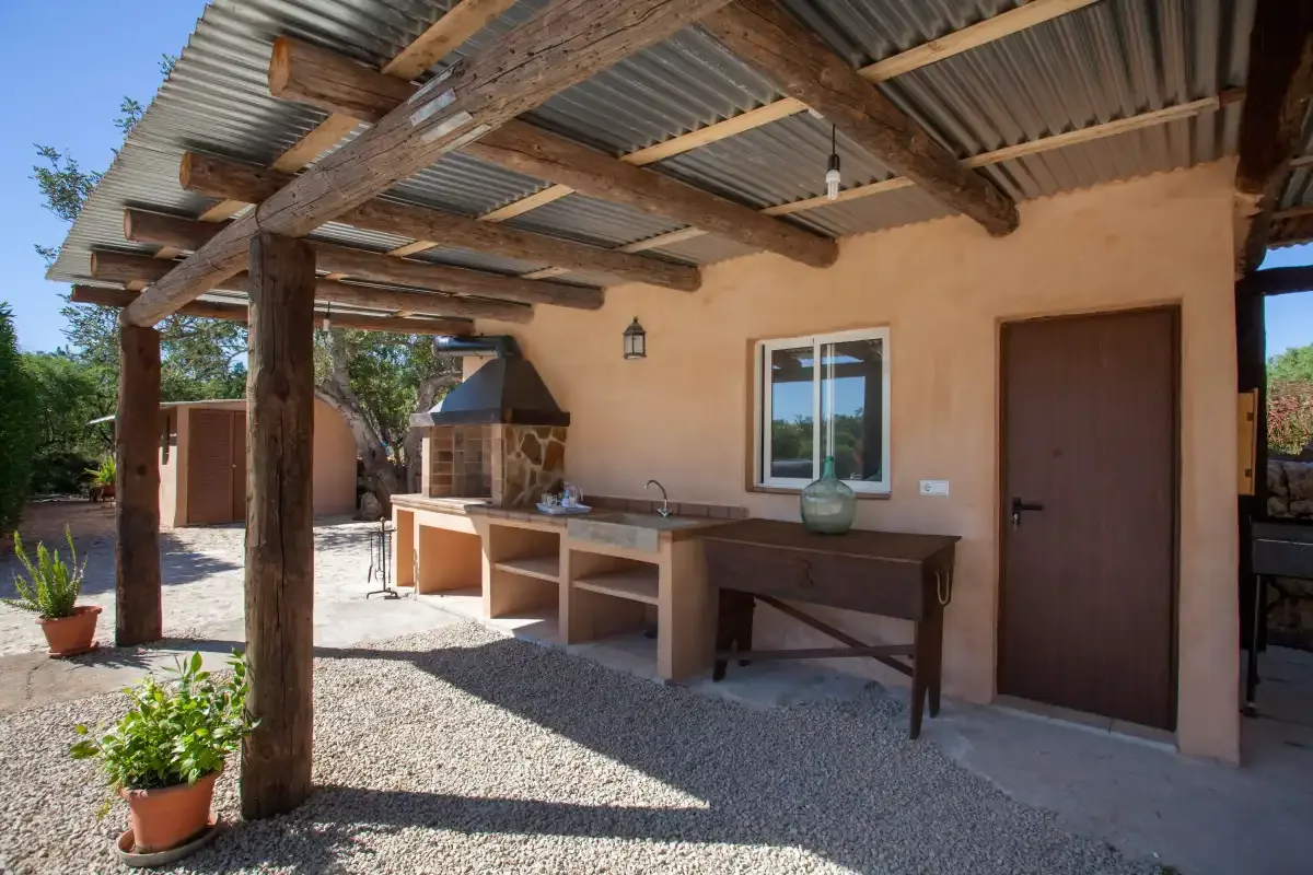 A covered outdoor patio with a long counter and a built-in grill.