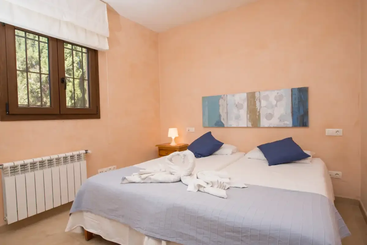A bedroom with a made bed and abstract artwork above it.