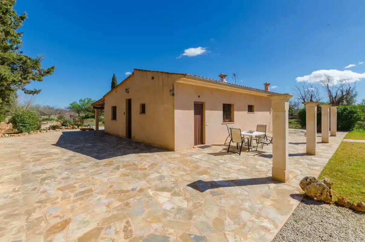 A house with a stone-paved patio and outdoor table under a clear blue sky.