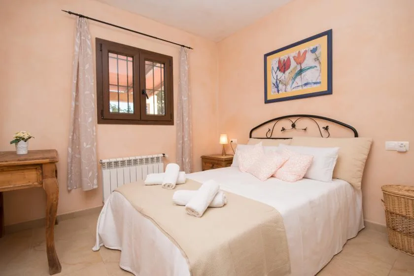 A bedroom with a neatly made bed and a window with curtains.
