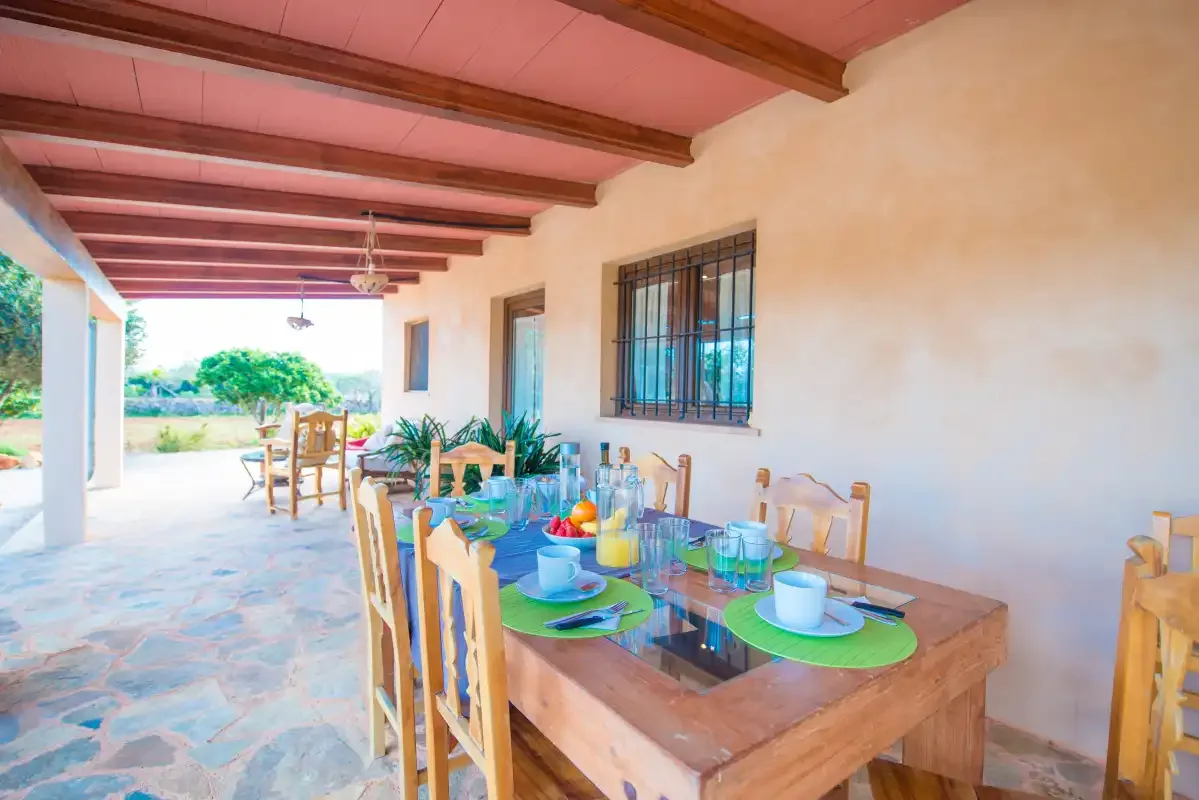 A covered outdoor dining area with a wooden table and chairs.