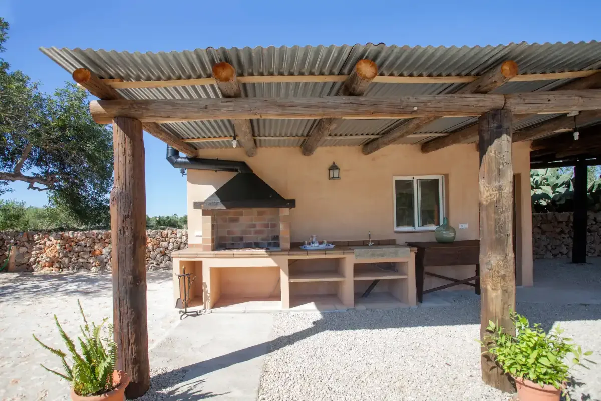 A covered outdoor kitchen with a brick barbecue and stone worktop.