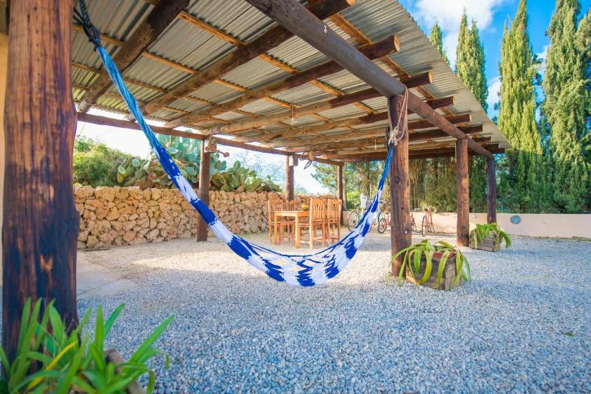 A shaded outdoor seating area with a blue hammock over gravel.