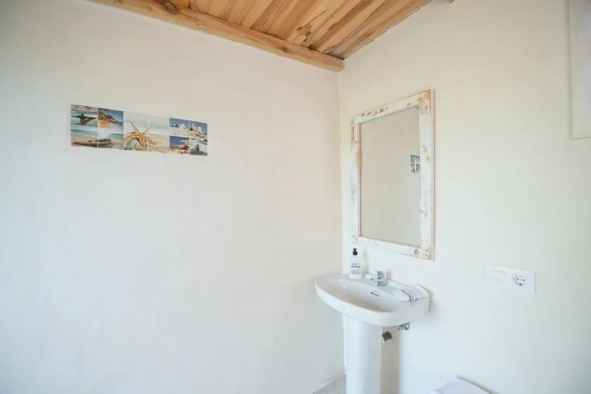 A bright bathroom with a pedestal sink and a wall mirror.