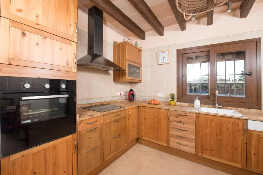 A kitchen with wooden cabinets, a cooking range, and a window above the sink.