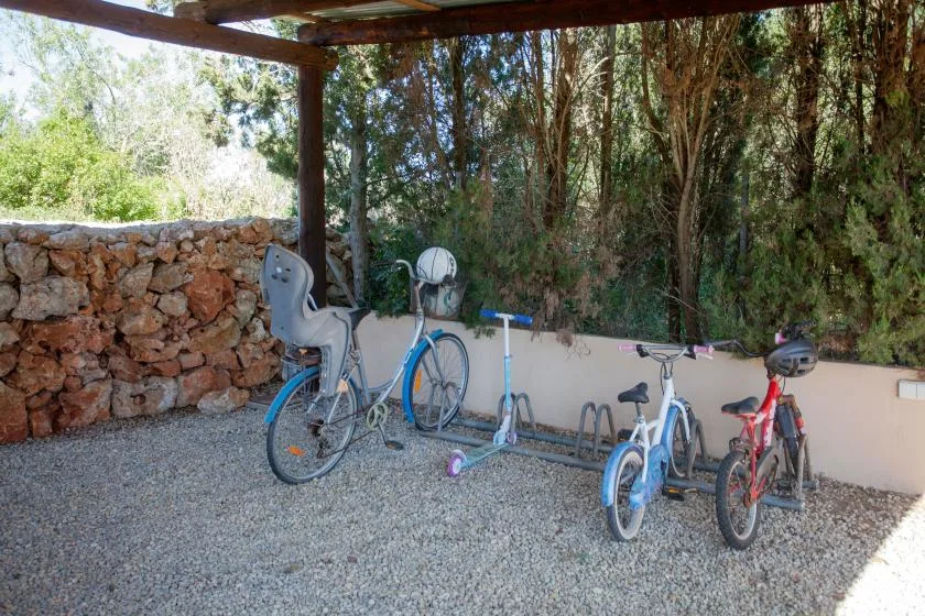 A sheltered outdoor area with several bicycles parked beside a low wall.