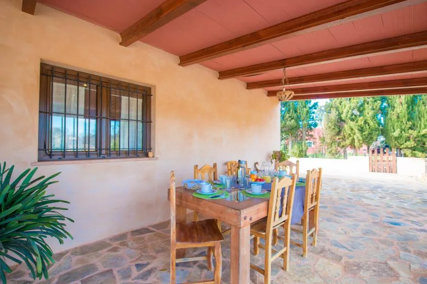 Un comedor en un patio cubierto con una mesa y sillas de madera.