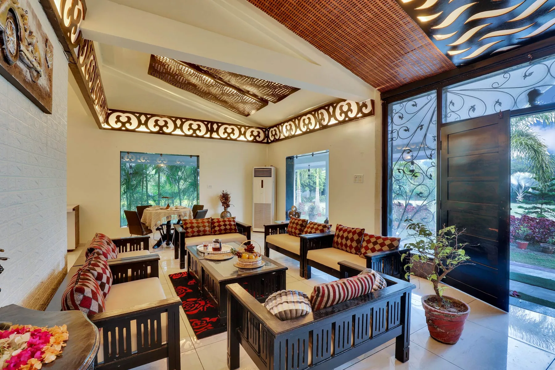 A spacious living room with dark seating, patterned cushions, and large glass doors.