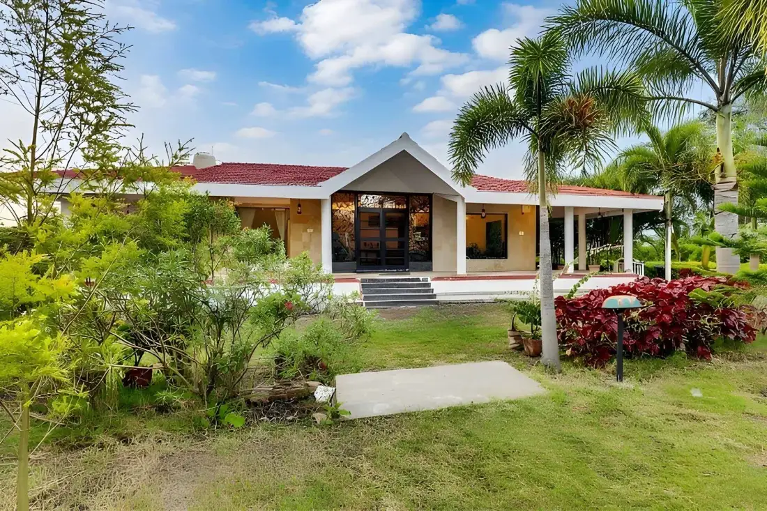 A low building with a red roof sits among palm trees and landscaped gardens.
