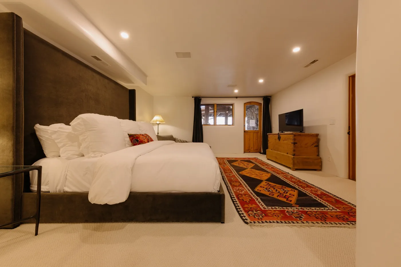 A bedroom with a large bed and a patterned rug on the floor.