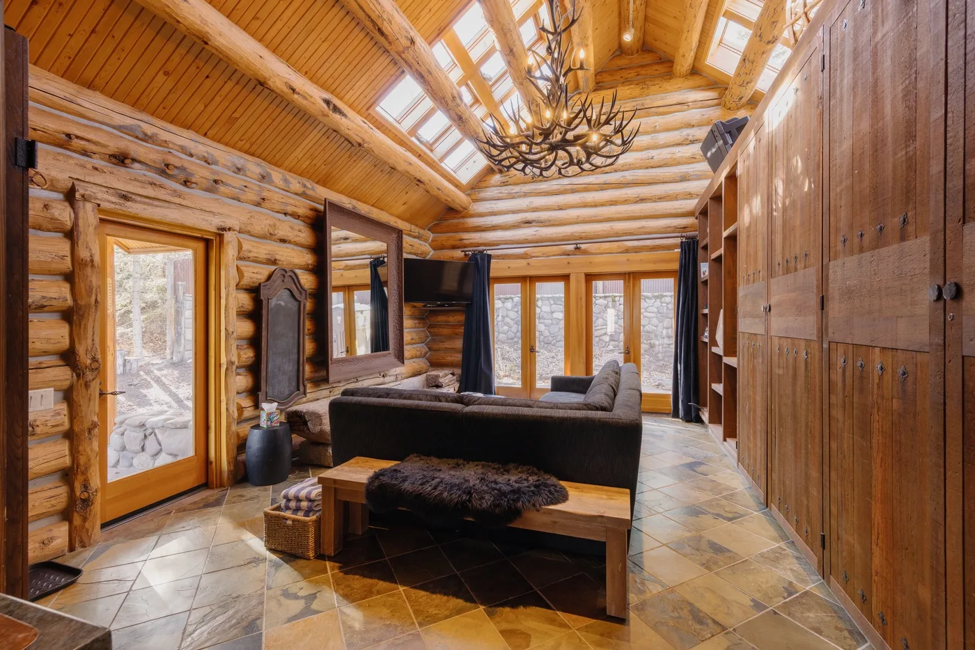 A timber great room with a seating area beneath a skylit ceiling.