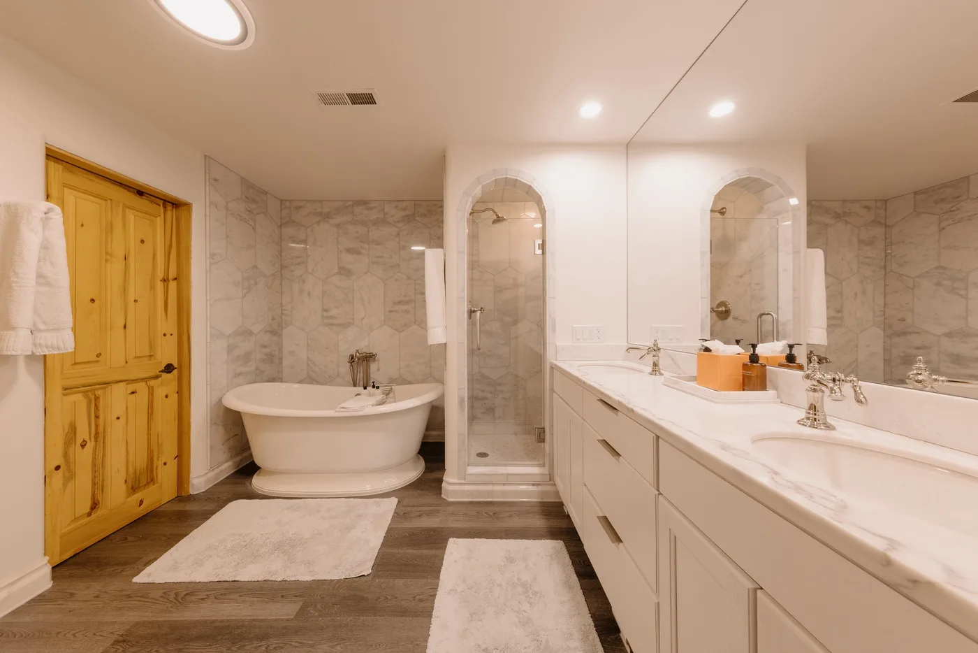 A bathroom with a bathtub, glass shower, and long vanity.
