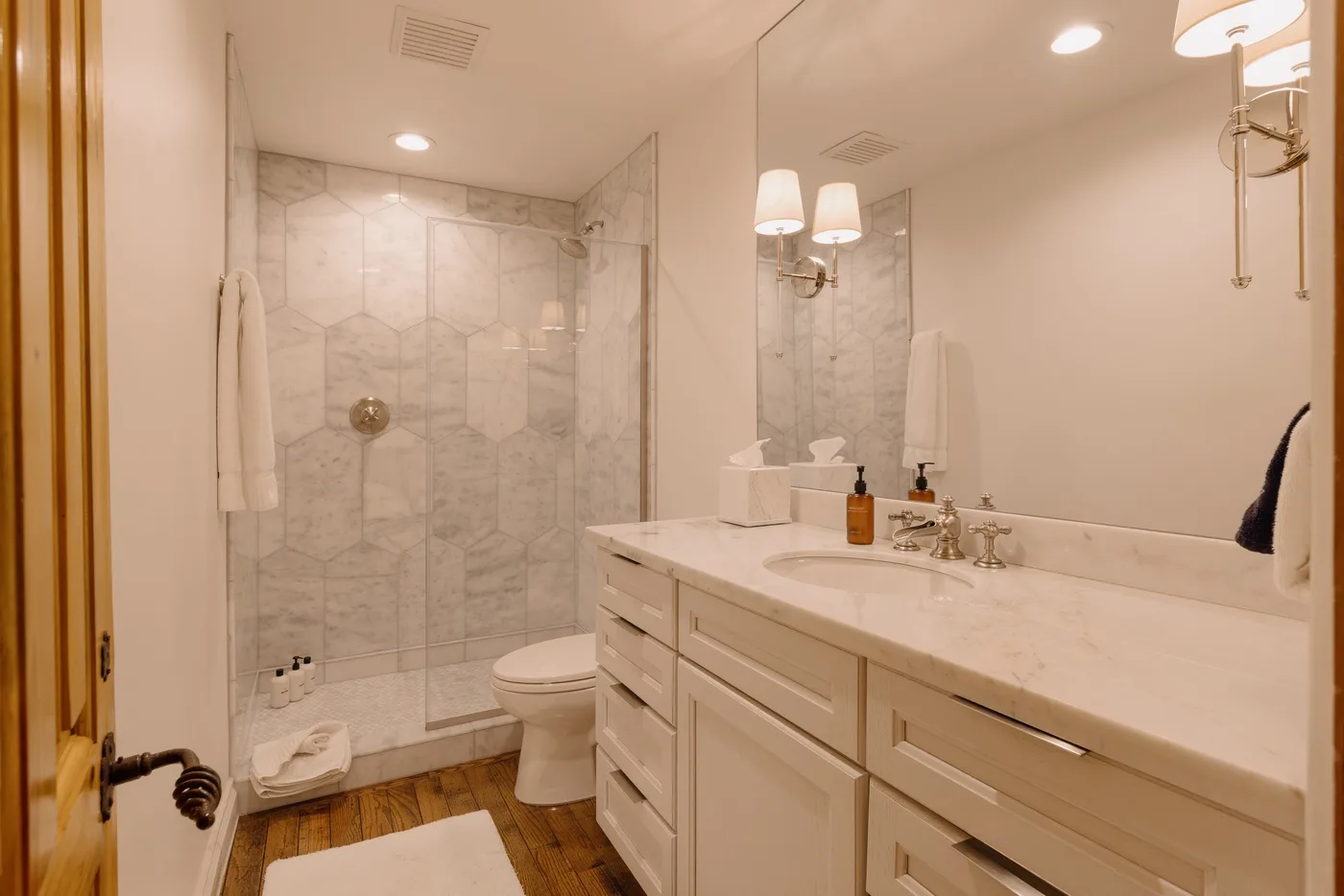 A bathroom with a marble-patterned shower and a long vanity.