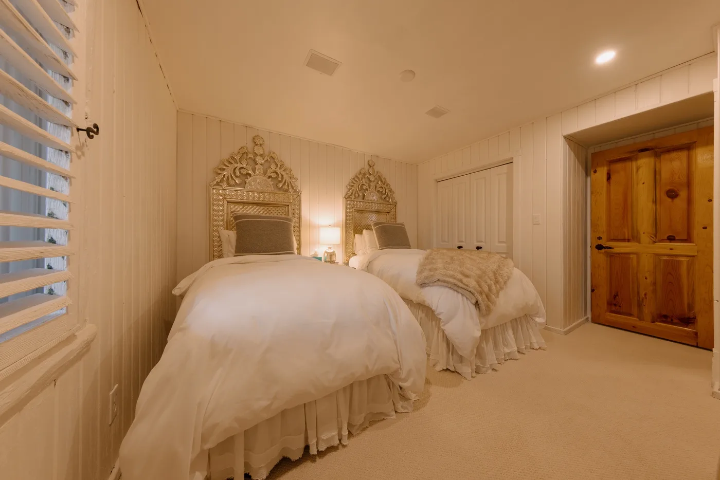 A bedroom with two beds and ornate headboards.