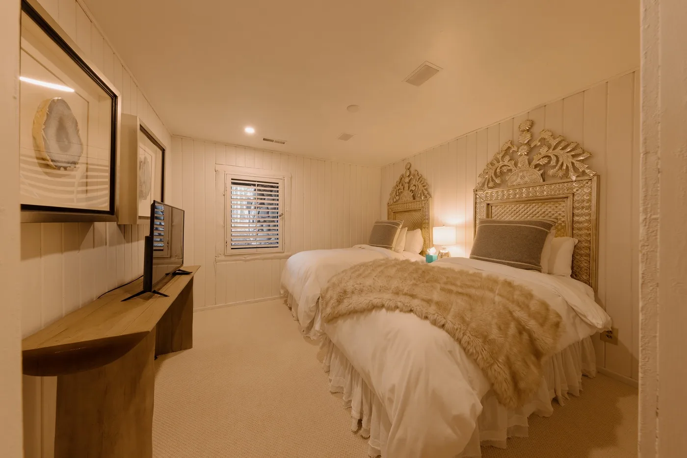 A bedroom with a large bed, ornate headboards, and warm lighting.
