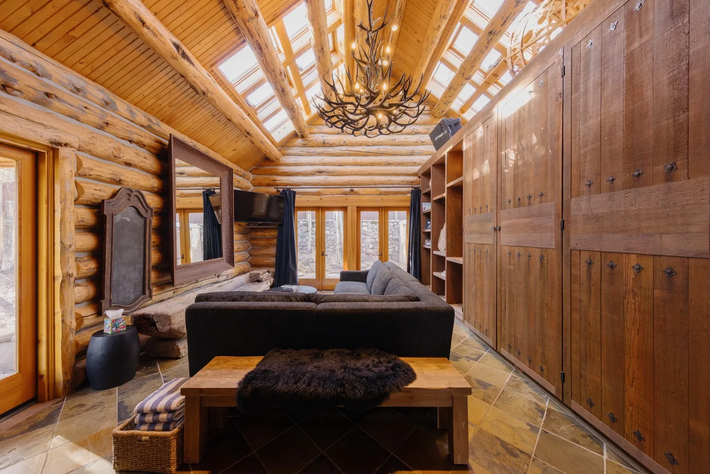 A log-cabin living room with seating, a wooden coffee table, and skylights.