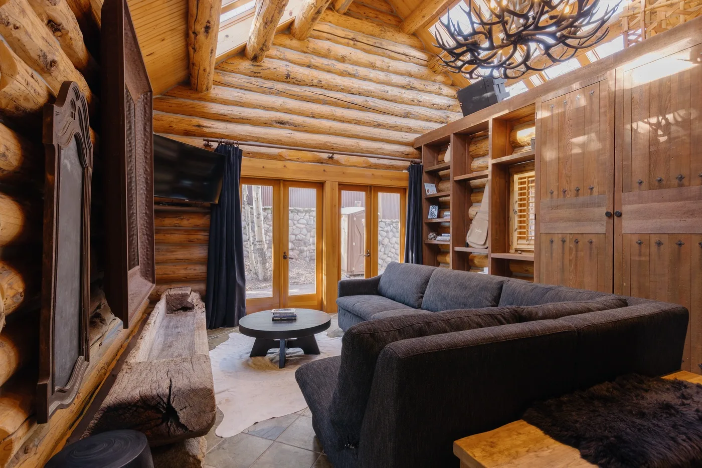 A log-cabin living room with seating around a low coffee table.
