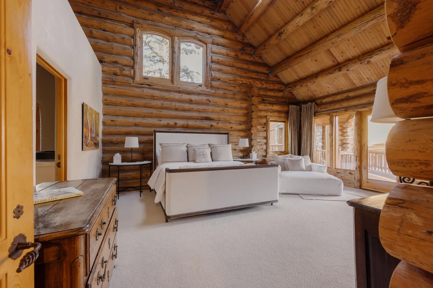 A bedroom with a bed and seating in a wood-paneled room.