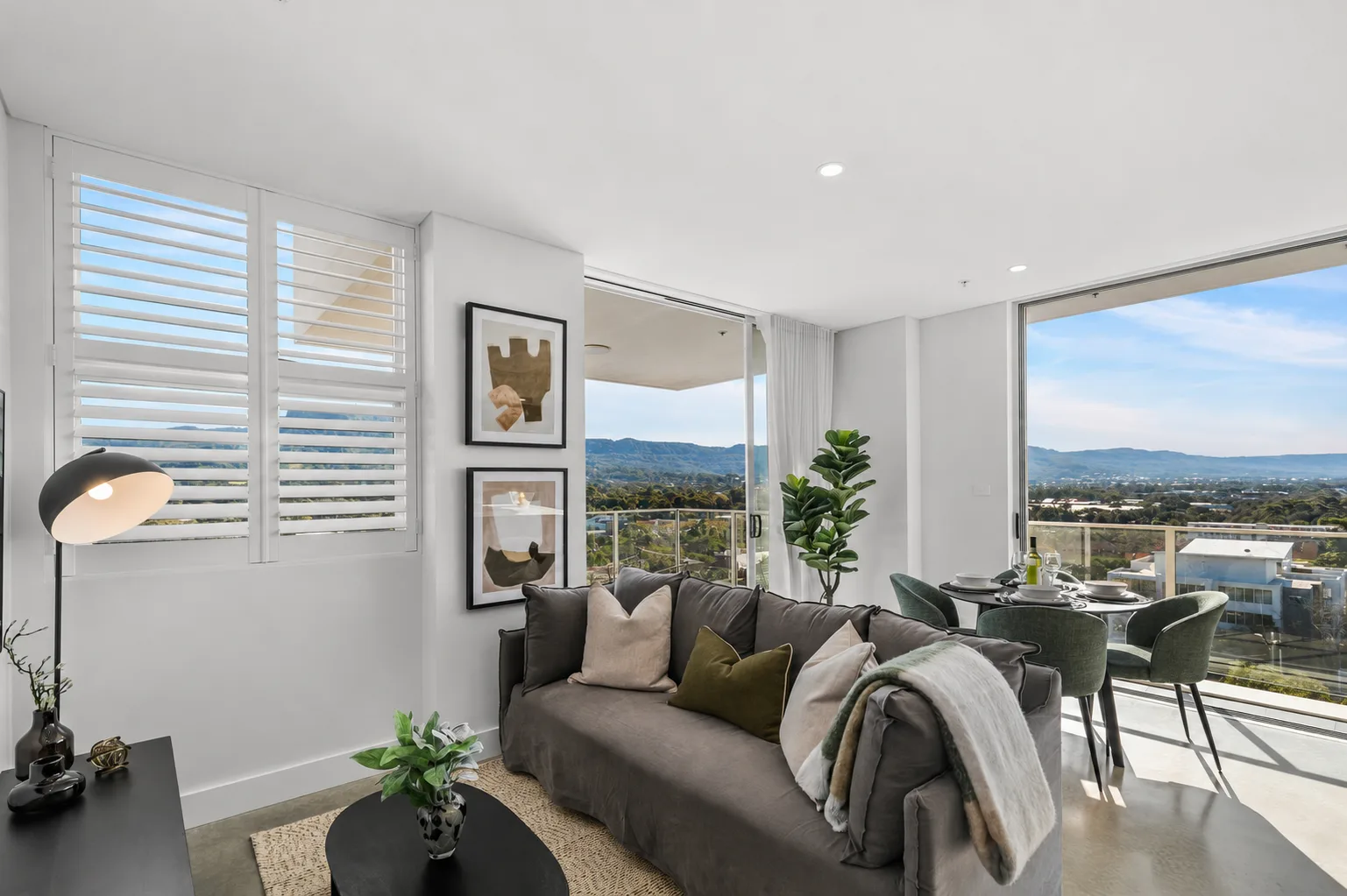 Open-plan living and dining area with seating beside large windows overlooking the hills.