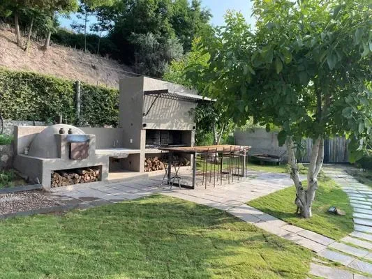 Un patio al aire libre con una parrilla integrada y una mesa junto al césped.