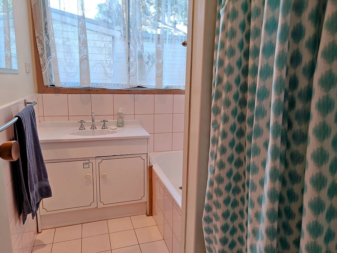 A bathroom with a sink, bathtub, and patterned shower curtain.